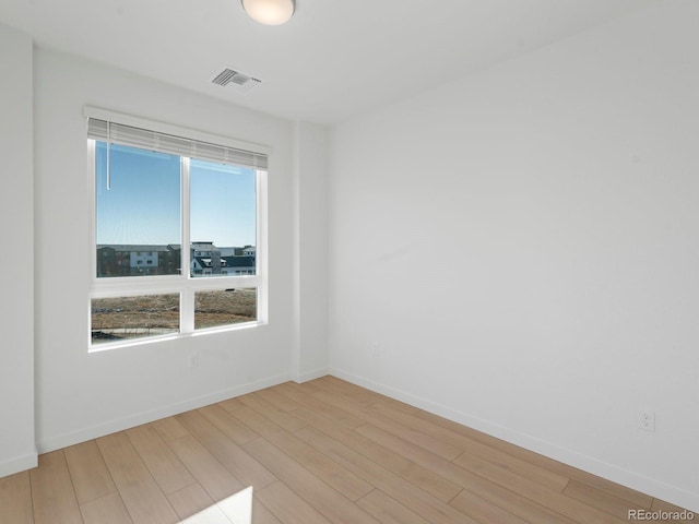 spare room featuring visible vents, light wood-style flooring, and baseboards