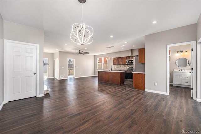 kitchen featuring open floor plan, dark wood finished floors, appliances with stainless steel finishes, light countertops, and decorative backsplash