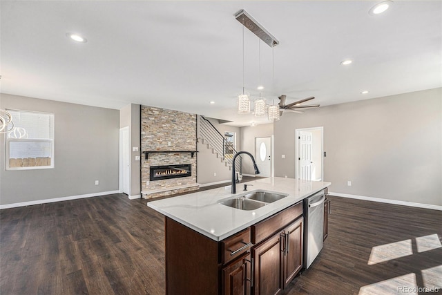 kitchen with open floor plan, dishwasher, a fireplace, and a sink