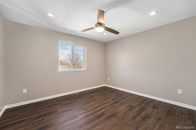 unfurnished room featuring dark wood-type flooring, visible vents, and baseboards