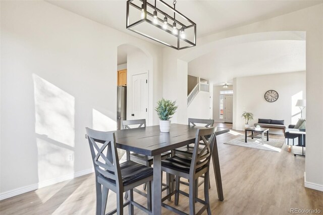 4844 Mt Evans St, Brighton, CO 80601 - dining space with arched walkways, light wood-type flooring, baseboards, and stairs