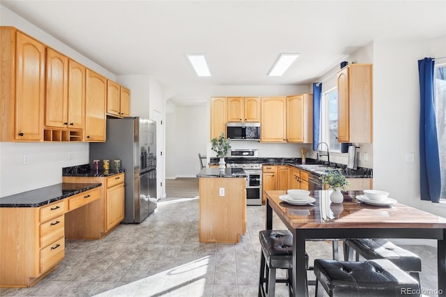 4844 Mt Evans St, Brighton, CO 80601 - kitchen featuring appliances with stainless steel finishes, light brown cabinetry, a center island, a sink, and dark stone counters
