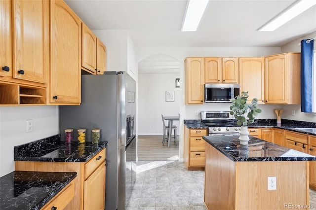 4844 Mt Evans St, Brighton, CO 80601 - kitchen featuring stainless steel appliances, light brown cabinets, arched walkways, dark stone counters, and a kitchen island