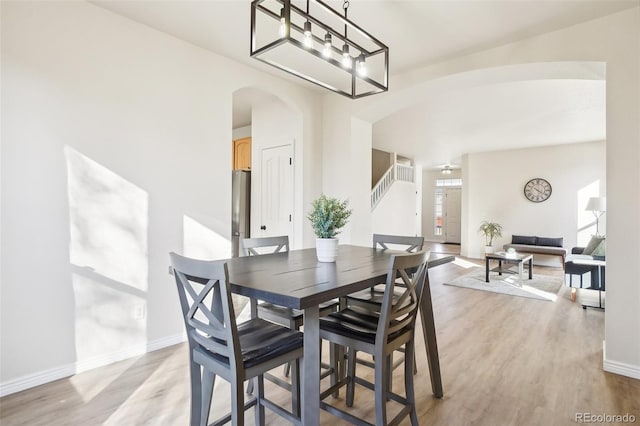 4844 Mt Evans St, Brighton, CO 80601 - dining area featuring arched walkways, light wood finished floors, and stairway