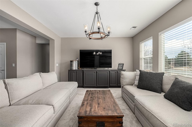 living room featuring light carpet, visible vents, and a notable chandelier