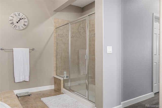 bathroom featuring a shower stall, baseboards, and tile patterned floors