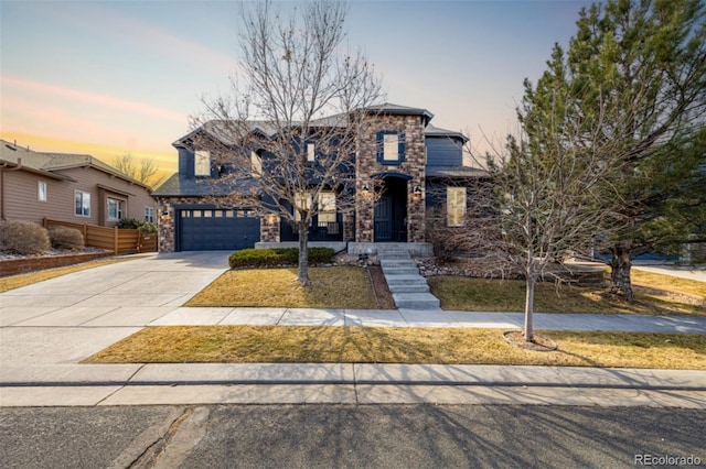 view of front of property featuring driveway, stone siding, and an attached garage