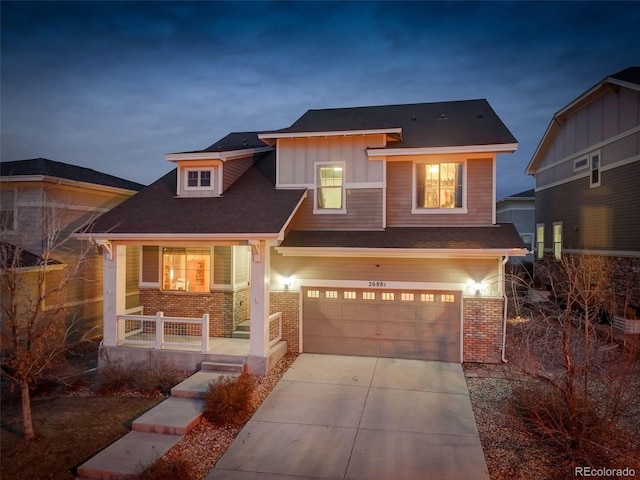 view of front of house with board and batten siding, covered porch, brick siding, and concrete driveway