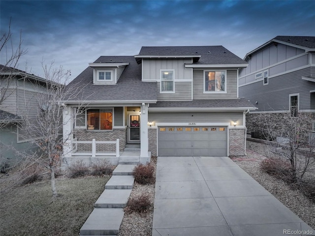 view of front of house with driveway, a garage, roof with shingles, covered porch, and brick siding