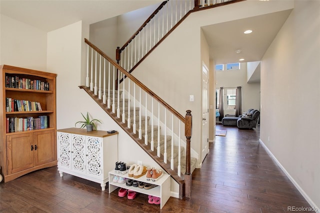 staircase featuring recessed lighting, a towering ceiling, baseboards, and hardwood / wood-style flooring