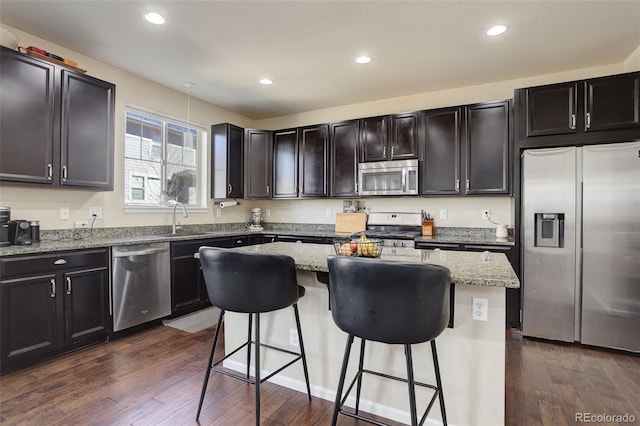 kitchen with a breakfast bar, a center island, dark wood finished floors, appliances with stainless steel finishes, and a sink