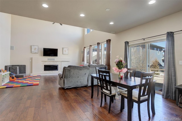 dining area featuring a healthy amount of sunlight, recessed lighting, dark wood finished floors, and a glass covered fireplace