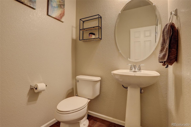 half bathroom with baseboards, a textured wall, toilet, and wood finished floors