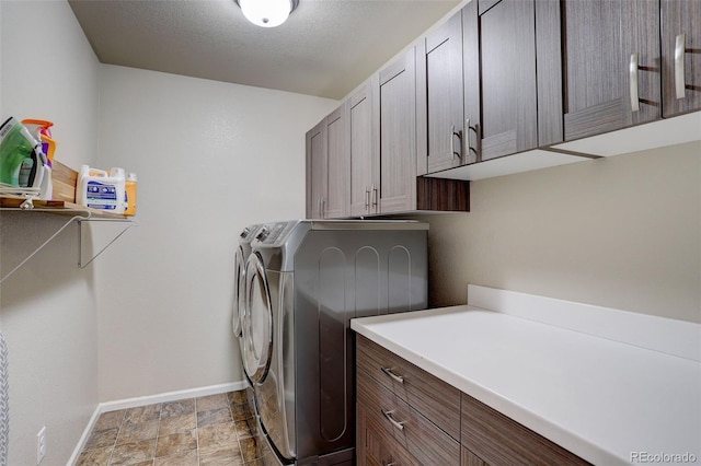 washroom with cabinet space, stone finish floor, a textured ceiling, washer and dryer, and baseboards