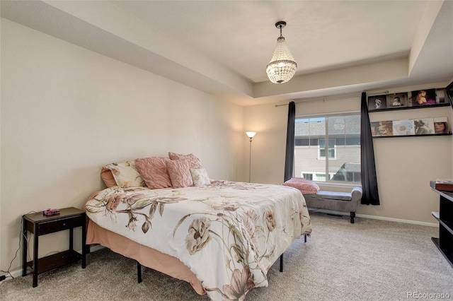 carpeted bedroom with a raised ceiling and baseboards