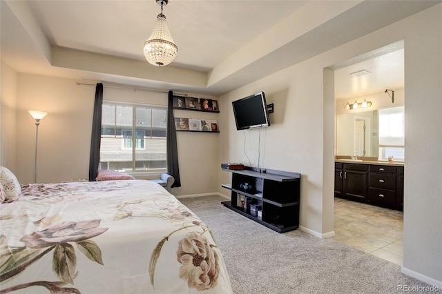 bedroom with light carpet, ensuite bath, a raised ceiling, and baseboards