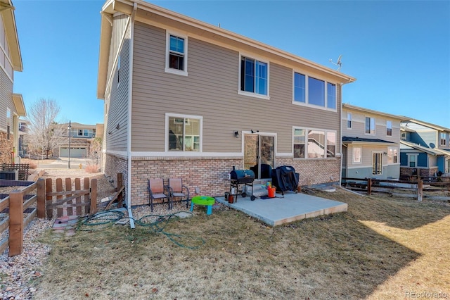 rear view of property featuring a yard, a patio area, brick siding, and a fenced backyard