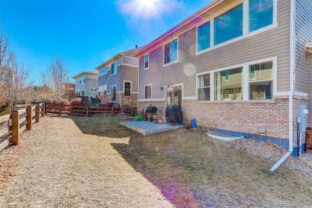 rear view of property with a fenced backyard, a patio, and brick siding