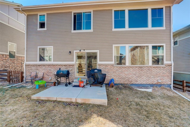 rear view of house featuring fence, a patio, and brick siding