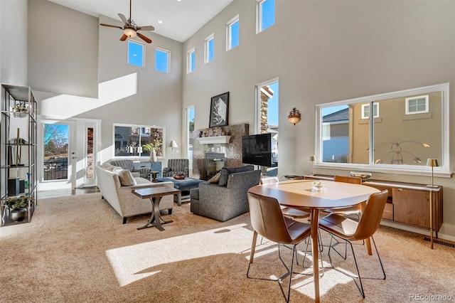 dining area featuring ceiling fan, light colored carpet, and a towering ceiling