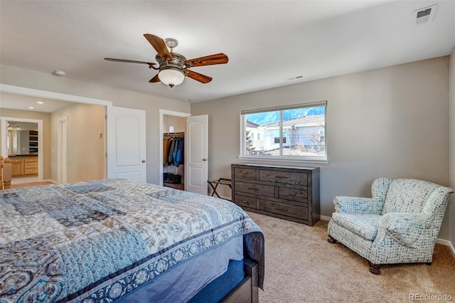 bedroom with a walk in closet, a closet, ceiling fan, and light colored carpet