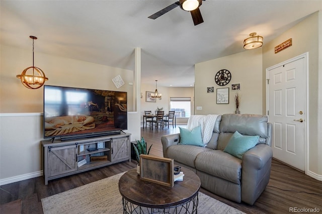 living room featuring dark wood-type flooring and ceiling fan with notable chandelier