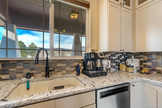 kitchen with tasteful backsplash, light stone countertops, dishwasher, and sink