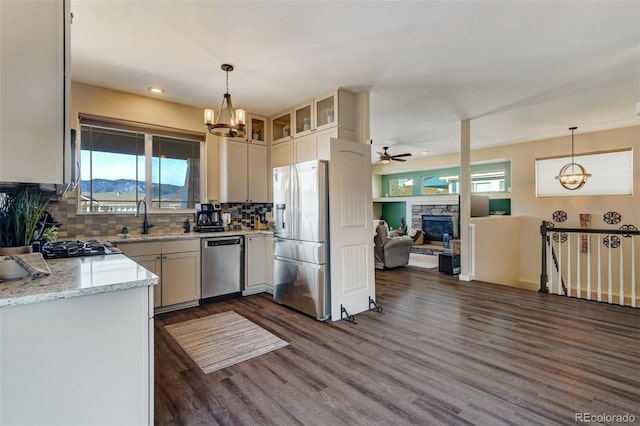 kitchen with a mountain view, hanging light fixtures, light stone countertops, a stone fireplace, and stainless steel appliances