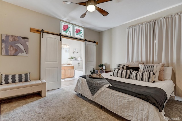 carpeted bedroom with ceiling fan, ensuite bath, and a barn door