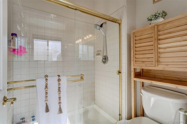 bathroom featuring toilet and a shower with door