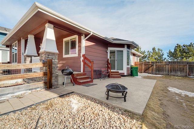 rear view of property featuring an outdoor fire pit and a patio area