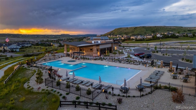 624 Simmental Loop, Castle Rock, CO 80104 - pool at dusk with a community pool, a patio, a hot tub, and a mountain view
