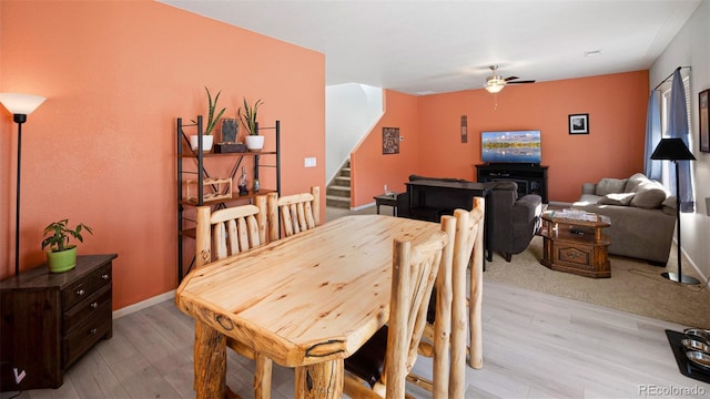 dining area with stairs, a ceiling fan, light wood-type flooring, and baseboards