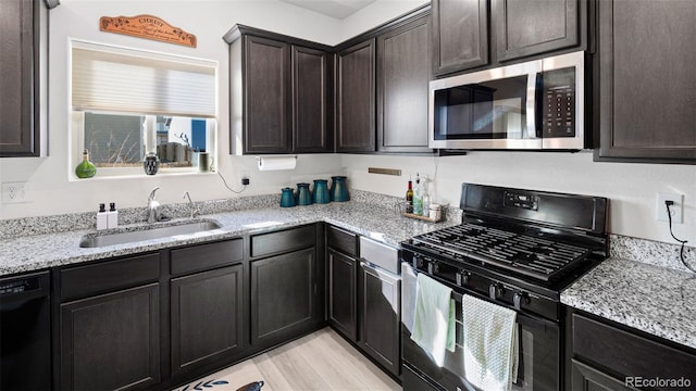 kitchen with black appliances, a sink, light stone counters, dark brown cabinetry, and light wood finished floors