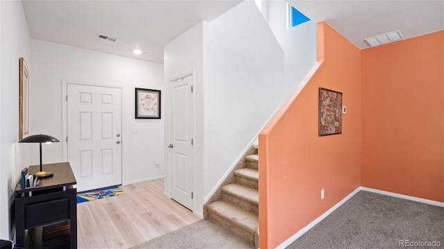 entrance foyer featuring visible vents, stairs, baseboards, and wood finished floors