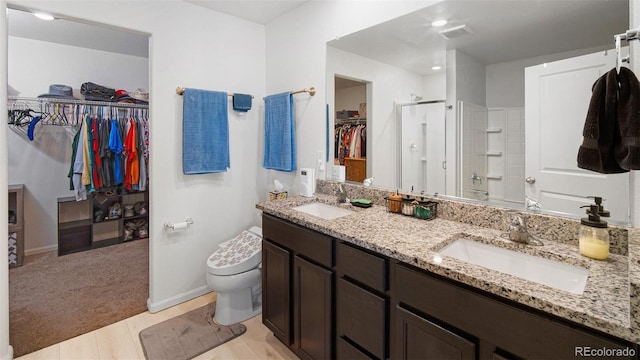 bathroom with double vanity, toilet, walk in shower, and a sink