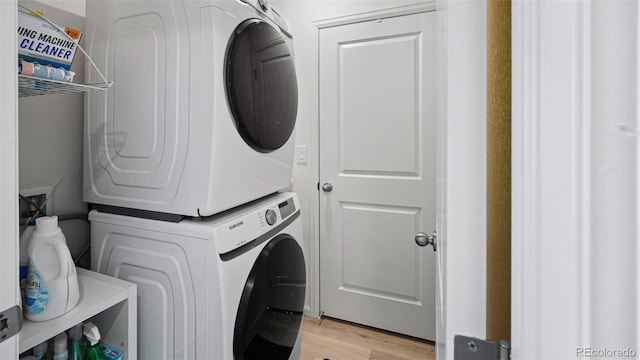 laundry area with laundry area, light wood-type flooring, and stacked washer and dryer