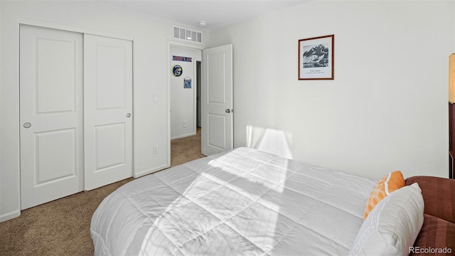 carpeted bedroom with a closet, visible vents, and baseboards