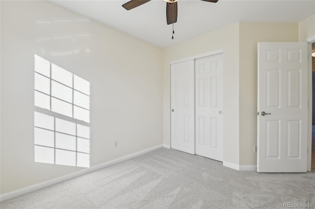 unfurnished bedroom with ceiling fan, a closet, baseboards, and carpet flooring