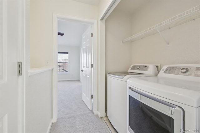 washroom with light carpet, laundry area, washer and clothes dryer, and baseboards