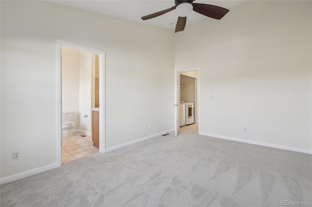 unfurnished bedroom featuring light colored carpet, connected bathroom, baseboards, and separate washer and dryer