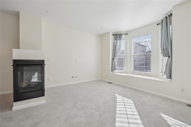 unfurnished living room featuring carpet flooring, visible vents, baseboards, and a multi sided fireplace