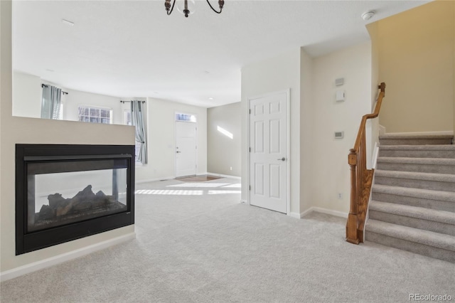 unfurnished living room with stairway, baseboards, carpet flooring, and a multi sided fireplace