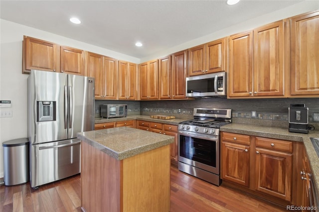 kitchen featuring stainless steel appliances, dark wood finished floors, tile counters, and decorative backsplash