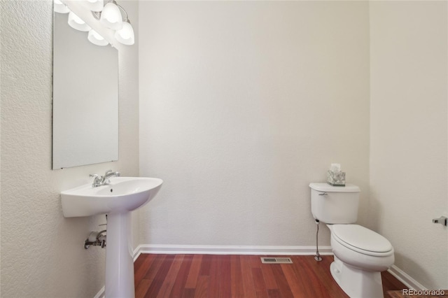 bathroom featuring toilet, visible vents, baseboards, and wood finished floors