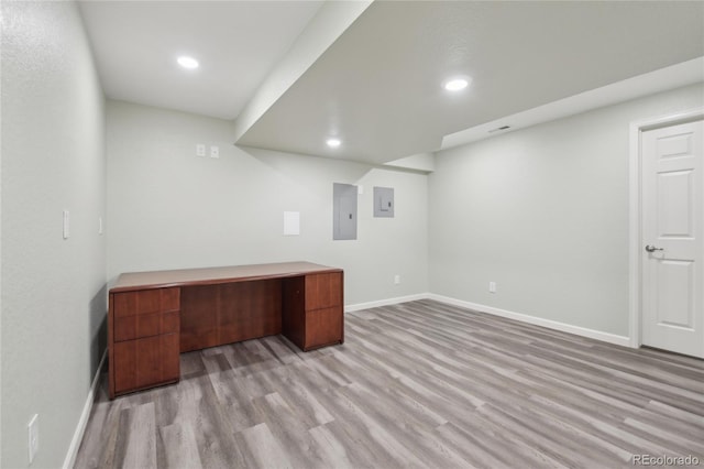 unfurnished office featuring recessed lighting, electric panel, and light wood-style flooring