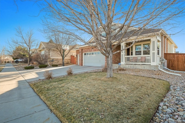 view of front of home with driveway, brick siding, fence, a porch, and a front yard