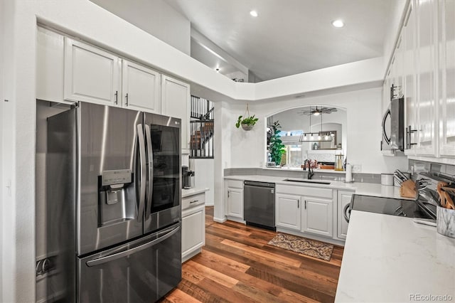 kitchen with stainless steel appliances, wood finished floors, a sink, and white cabinetry