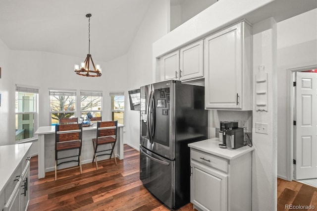 kitchen with dark wood-style flooring, white cabinets, vaulted ceiling, light countertops, and stainless steel fridge