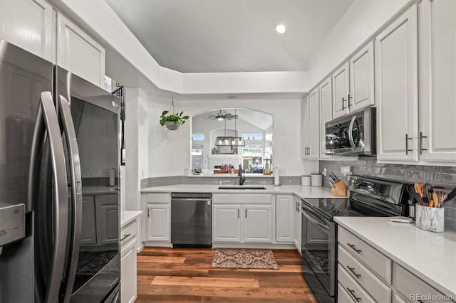 kitchen with dark wood-style floors, arched walkways, stainless steel appliances, light countertops, and a sink